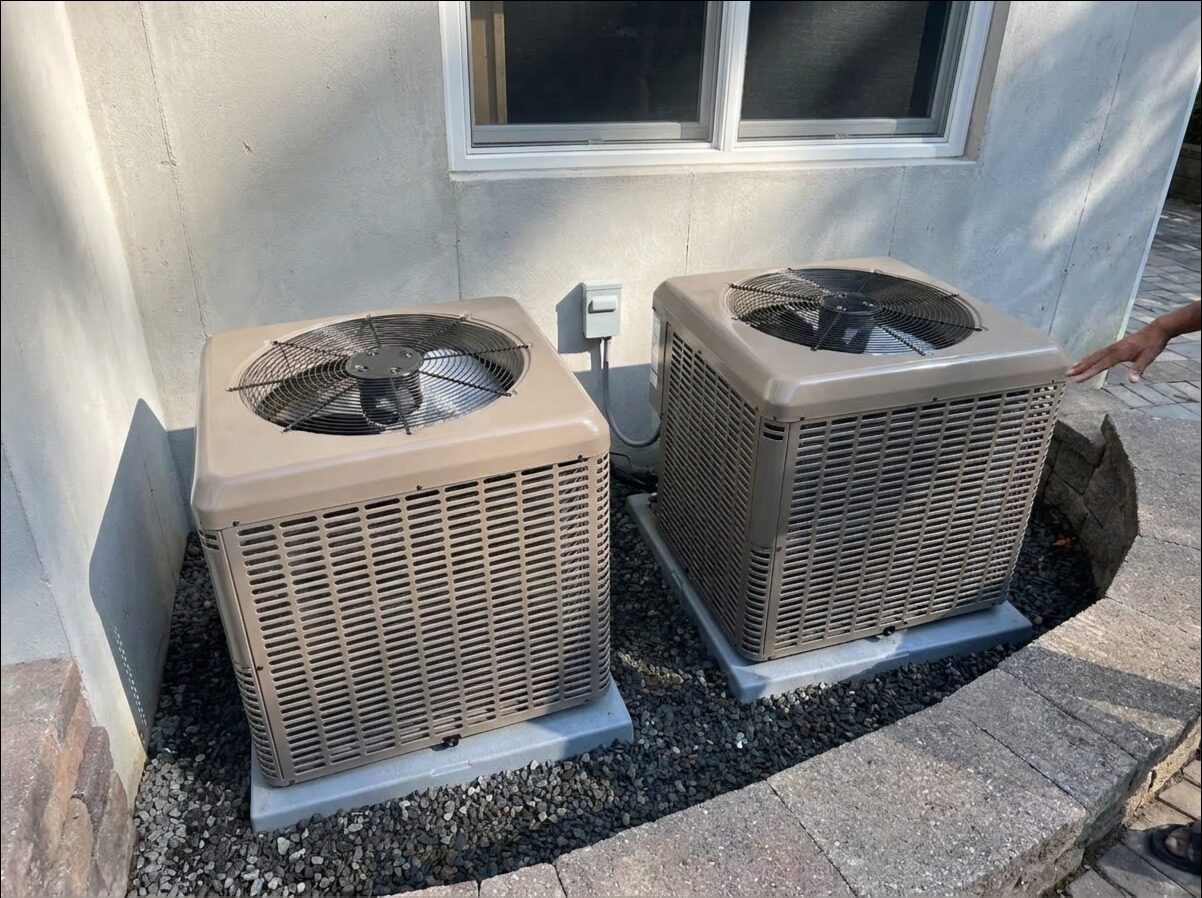 Two central air conditioning condensers installed on a concrete pad